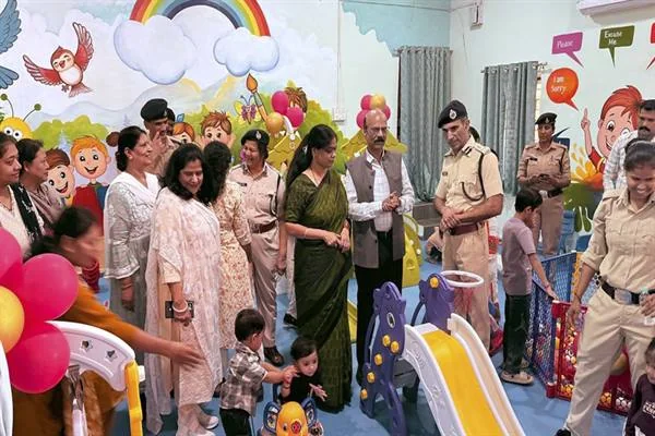 रंगीन दीवारों वाले झूलाघर में बच्चों के साथ खड़ी महिला पुलिसकर्मी और अधिकारी