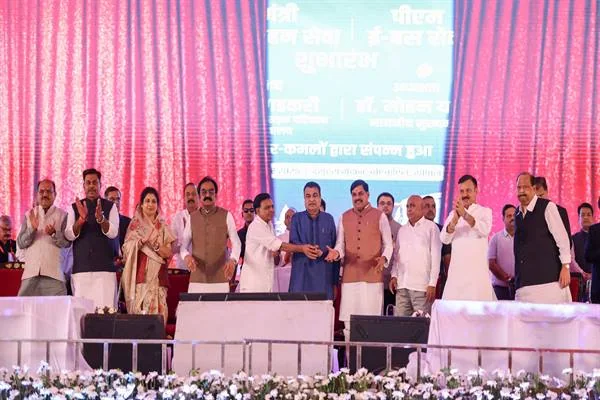 मंच पर बसों के शुभारंभ के मौके पर मुख्यमंत्री, केंद्रीय मंत्री नितिन गडकरी और अन्य अतिथि खड़े हैं, पीछे बैनर
